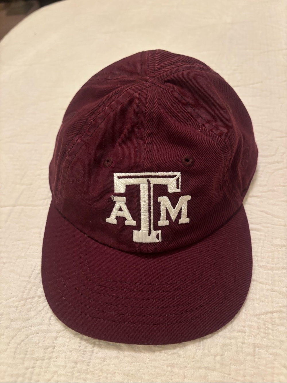 A&M baby baseball cap, elastic back w/ white embroidered A&M Logo & Lil’Aggie